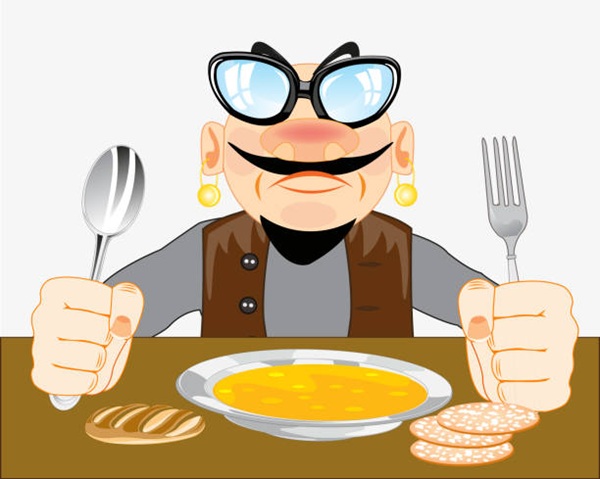 Man with fork and spoon in hand sits with meal at the table