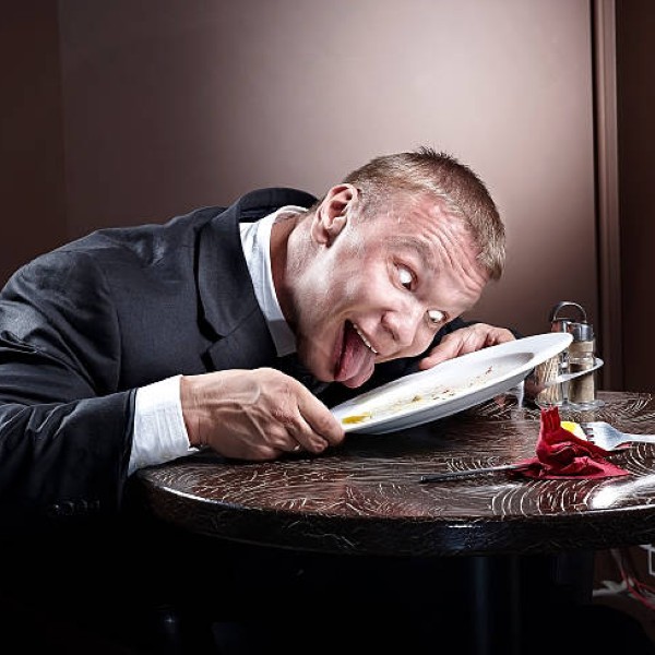 Muscular businessman eating and lick the plate