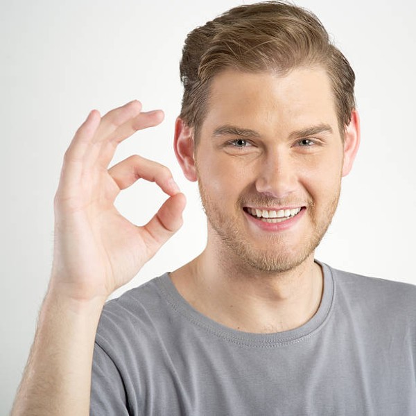 Young man gesturing OK sign on light background