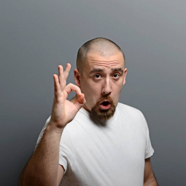 Portrait of a man showing thumb up or ok sign against gray background
