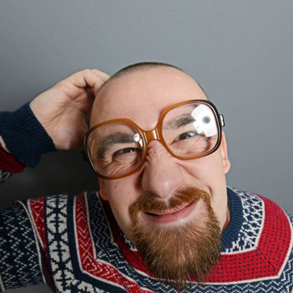 Portrait of a nerd with glasses and retro sweater against gray background