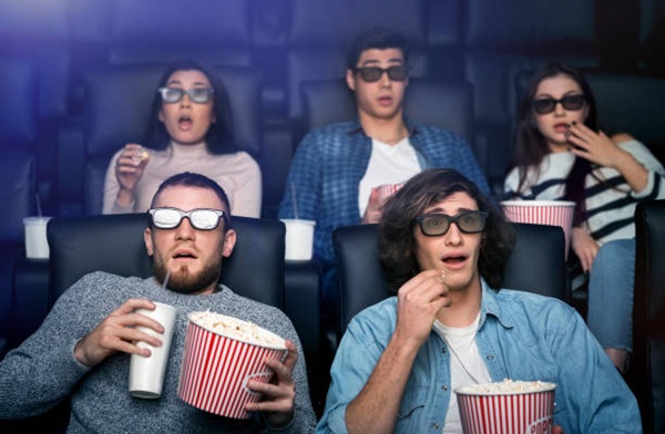 Young people in 3D glasses watching horror movie in cinema