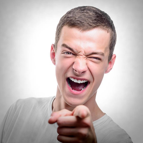 Portrait of young angry man points finger. Toned photo.