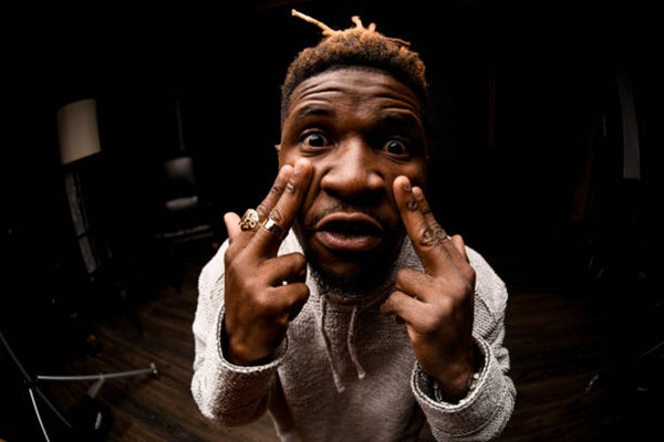 Afro american guy in gray sweater pointing with his fingers to his eyes